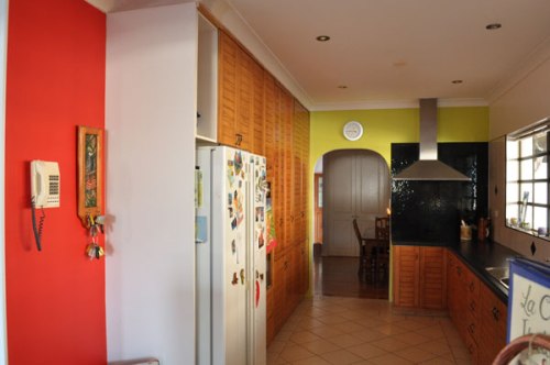 Long kitchen with oe feature wall bright red in the foreground and the back wall yellow